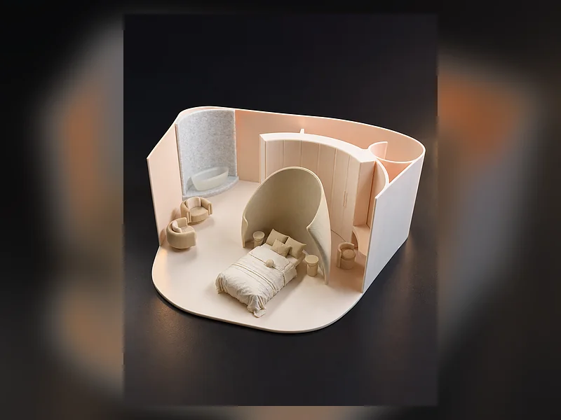 A miniature room model with curved walls, a bed and light-coloured furniture