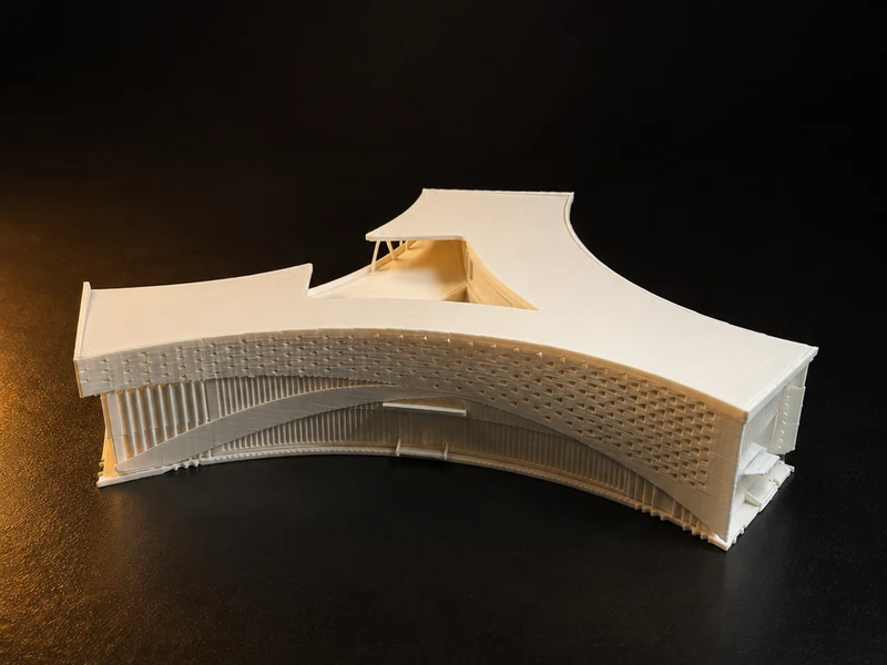 A white architectural model of a curved canopy on slender columns