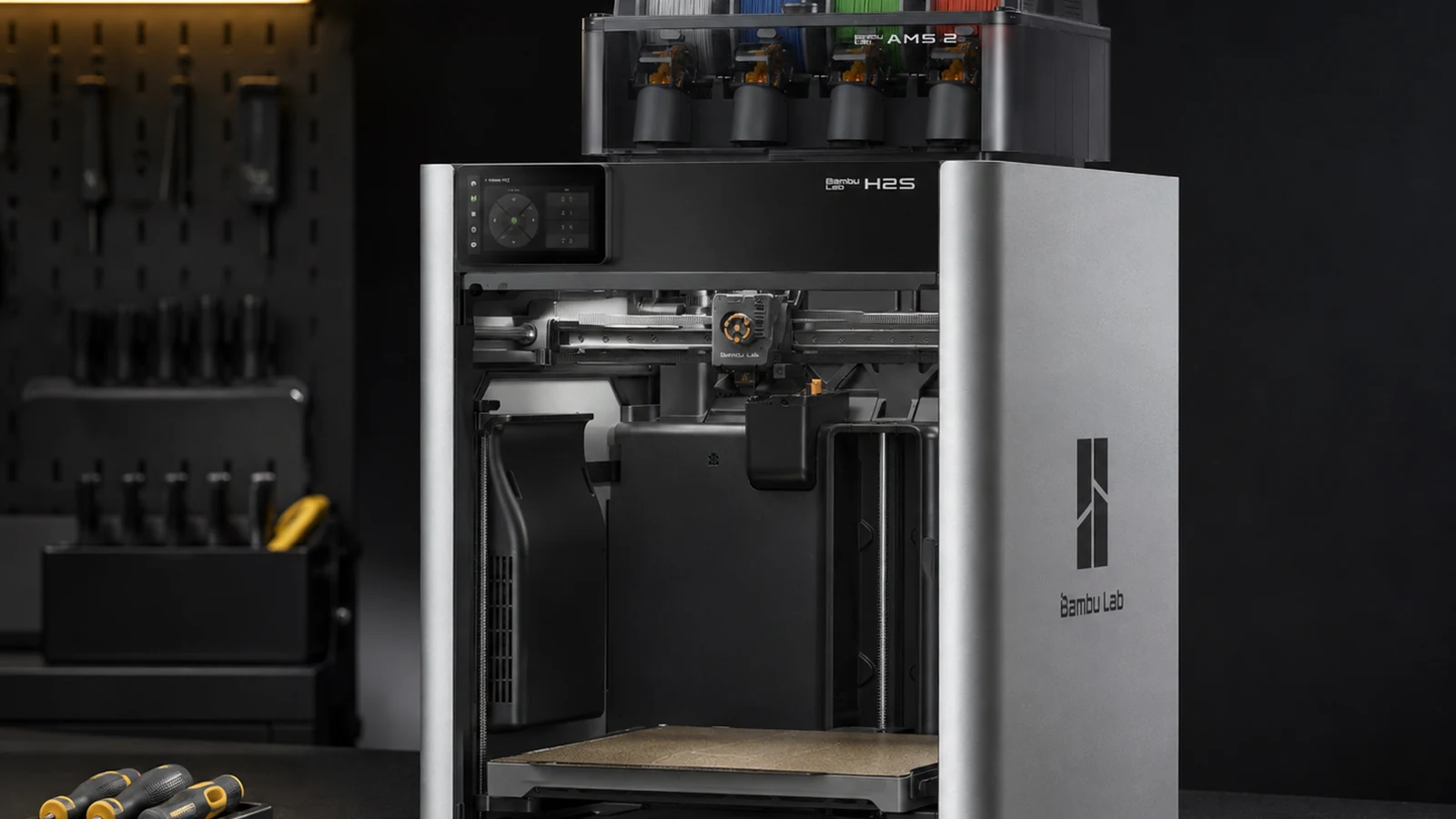 A printer opened at the front on a service bench, with screwdrivers and tools on a board behind it